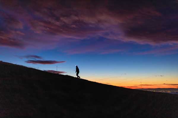 Un concorrente della Corsa della Bora al tramonto, in silhouette sul crinale del Carso