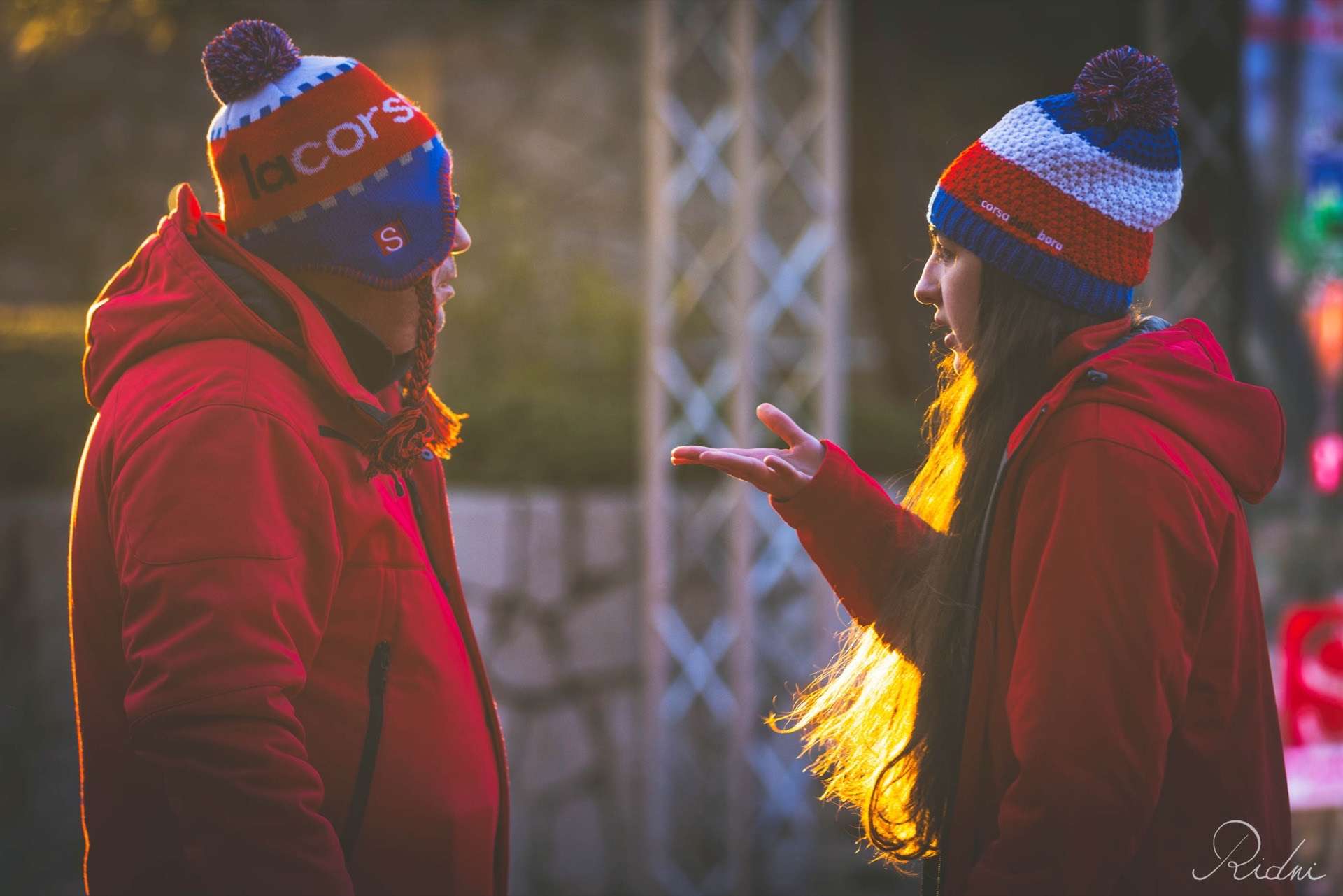 Due volontari della Corsa della Bora in giacca rossa parlano all'alba