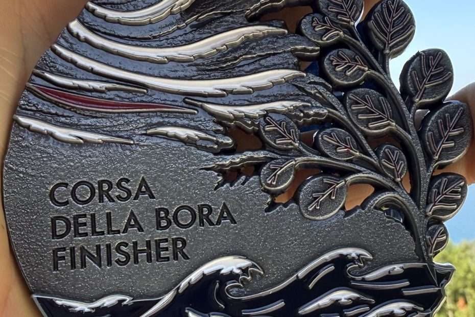 The 2027 Corsa della Bora finisher medal: the wind, the white crests of the Gulf of Trieste and a branch from the Karst.